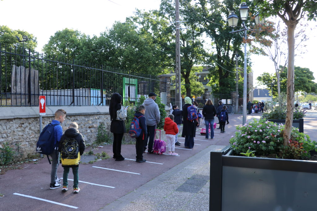 Elèves et parents font la queue dans la rue le jour de la rentrée scolaire